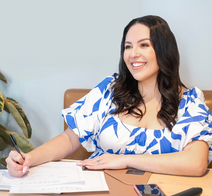 Sheereen, in a blue and white dress, signing marriage paperwork at a desk.