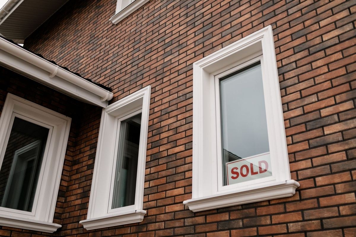 A brick house with a Sold sign displayed in the front window.