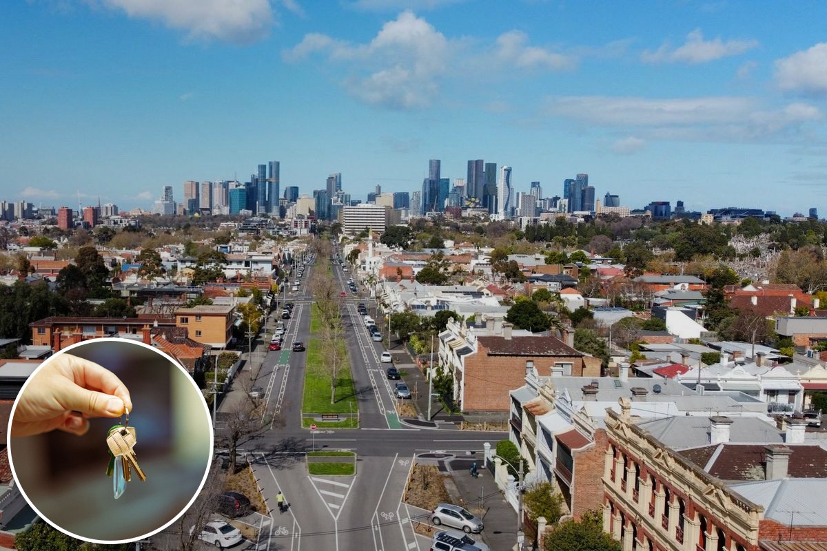 An aerial view over inner-Melbourne rooftops and a tree-lined boulevard, with the city skyline on the horizon.