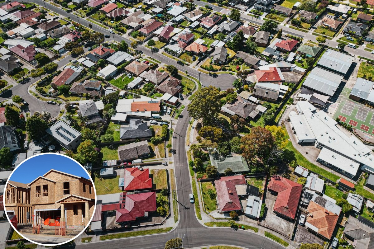 An aerial view over an established Melbourne suburb of tiled rooftops, streets and backyards.