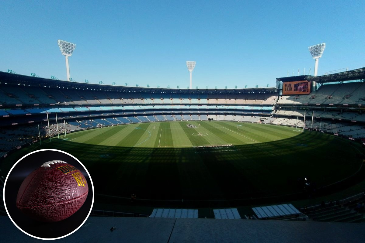 A wide-angle view across the empty Melbourne Cricket Ground, its stands and light towers under a clear blue sky.