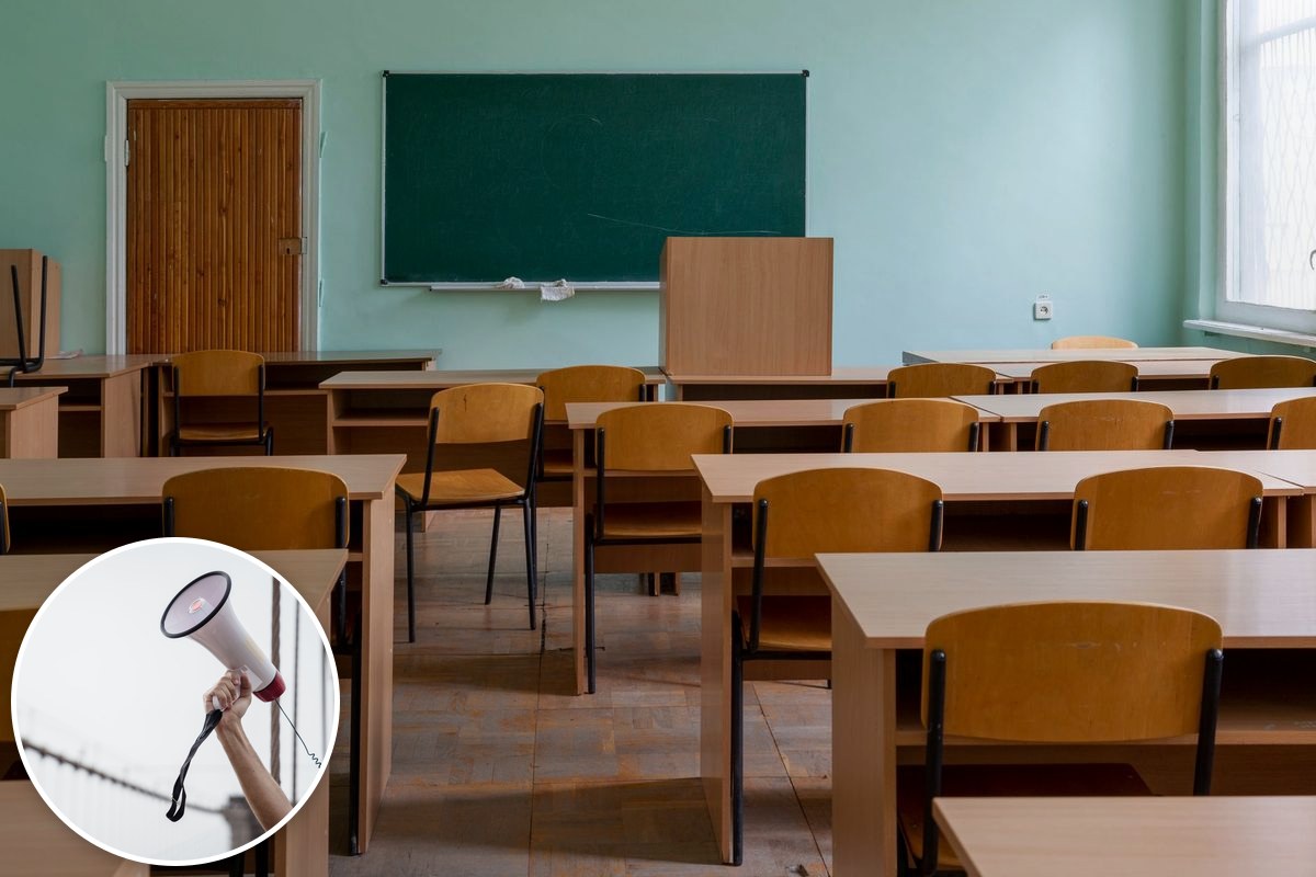 An empty classroom with wooden desks and chairs facing a green chalkboard.