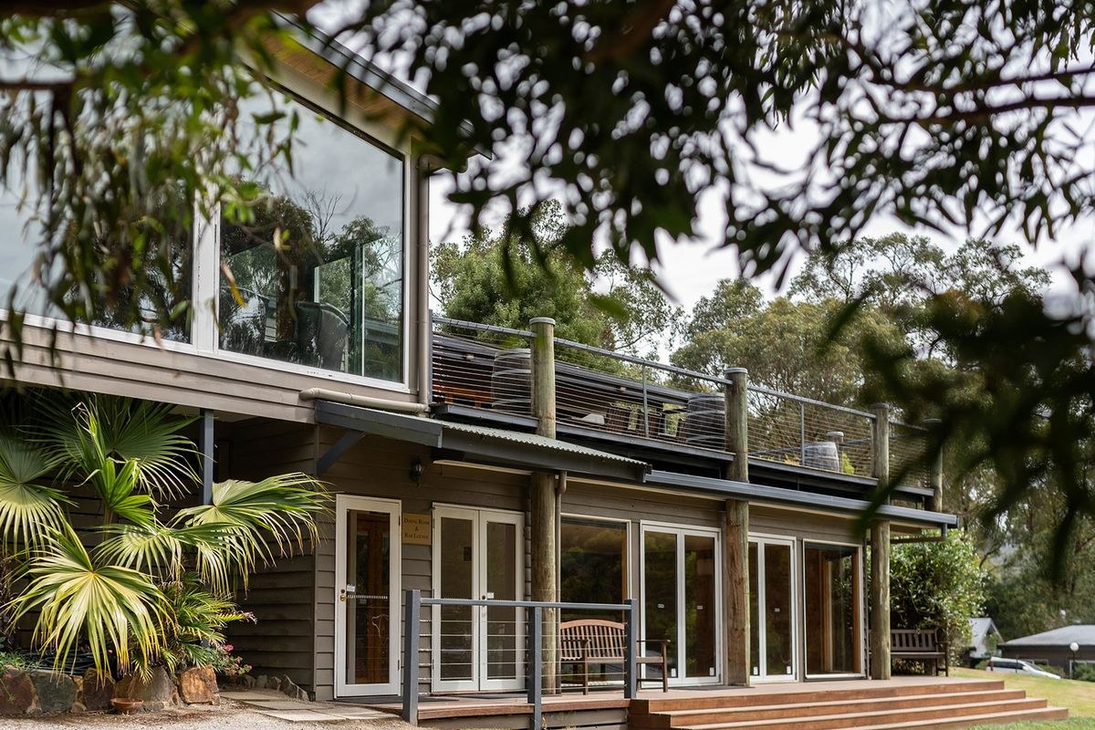The timber lodge at Yarra Valley Estate, its dining room and bar lounge framed by gum trees and palms.